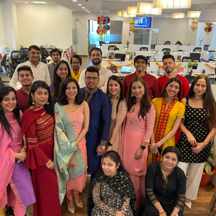 FinEdge team members dressed in festive traditional attire posing in the decorated office.