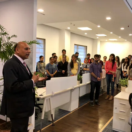 A speaker addressing FinEdge team members gathered in the office workspace.