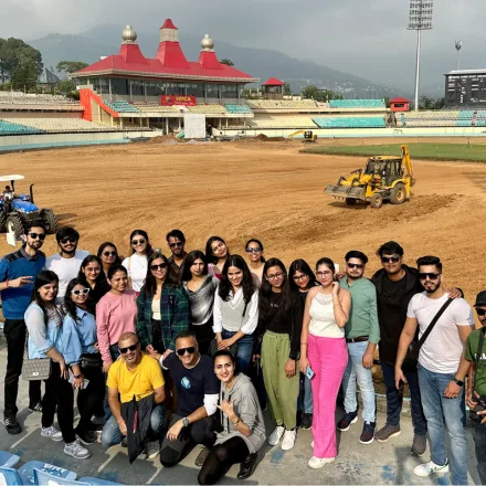 Large FinEdge team group photo at the Himachal Pradesh Cricket Association Stadium in Dharamshala.