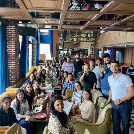 FinEdge team members gathered for a group photo at a restaurant with drinks and food on the tables.