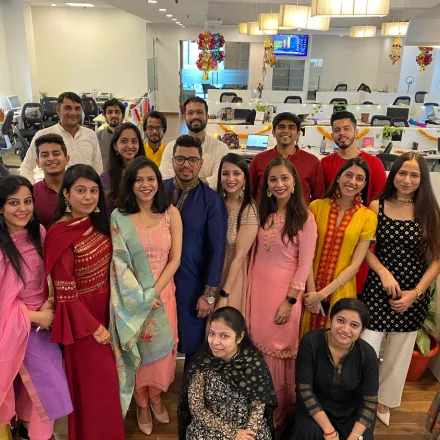 FinEdge team members dressed in festive traditional attire posing in the decorated office.