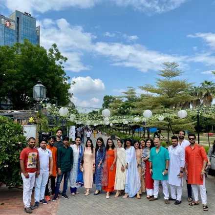 Team members in traditional Indian wear standing outdoors in a landscaped courtyard.