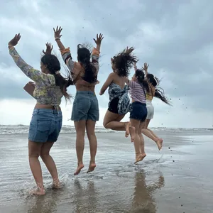 Women from the FinEdge team jumping joyfully on a beach with waves.