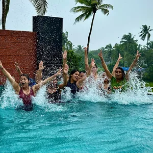FinEdge team members splashing in a swimming pool with palm trees in the background.