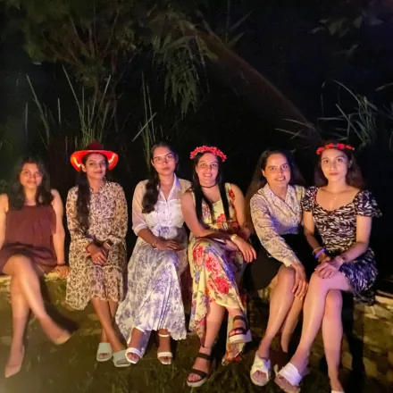 Women from the FinEdge team sitting together outdoors at night wearing floral accessories.