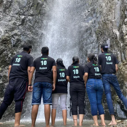 FinEdge team members wearing matching tenth-anniversary t-shirts standing in front of a waterfall.