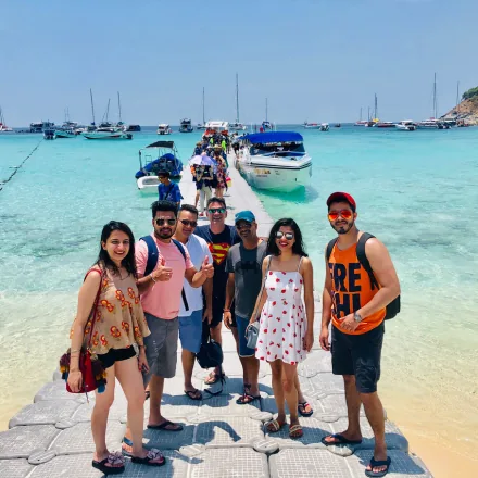 Group of FinEdge team members posing on a floating pier at a tropical beach with boats.