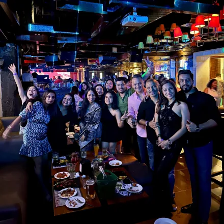 FinEdge team members celebrating together at a restaurant with food and drinks on the table.